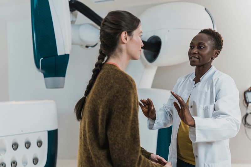 A clinician talking with a patient beside a scanner