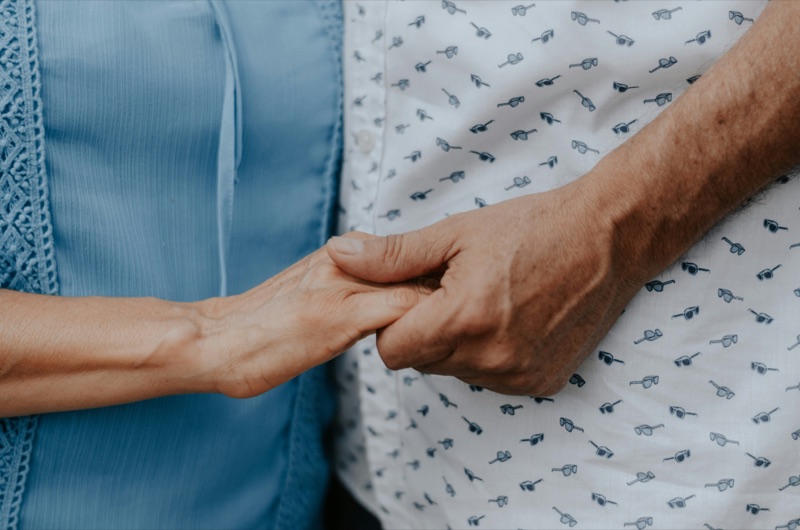 A visitor holding a patient&rsquo;s hand